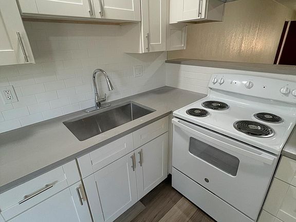 Brand new kitchen with electric range, stainless sink and subway tiles backsplash