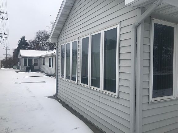 The sun porch has a door to a small cement outdoor patio. A street-side privacy fence is the view out the porch window.