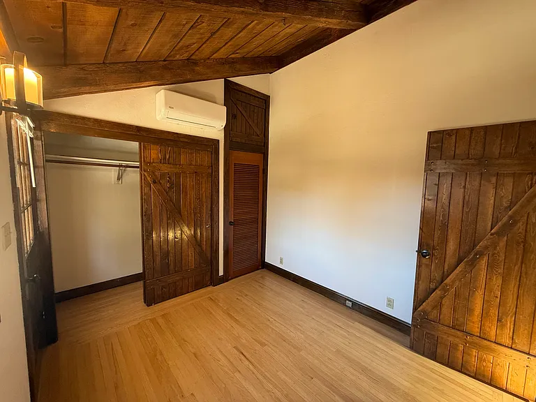Bedroom #4 features wooden valuted ceiling, one window, patio door to backyard and 2 closets with a split AC cooling unit.