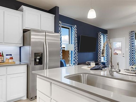 Kitchen featuring white cabinetry, stainless steel refrigerator with ice dispenser, pendant lighting, ceiling fan, and decorative backsplash