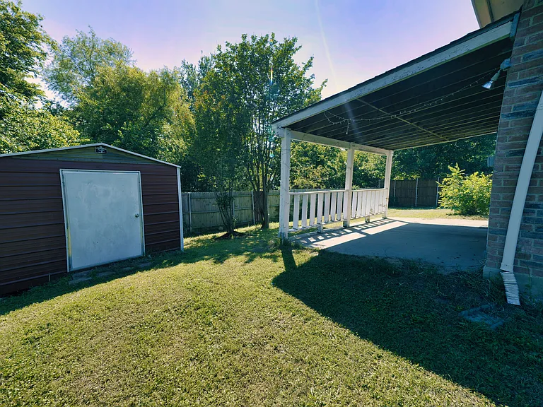 Enjoy outdoor living with a covered patio, storage shed, and a private gate opening directly to a peaceful nature trail and creek
