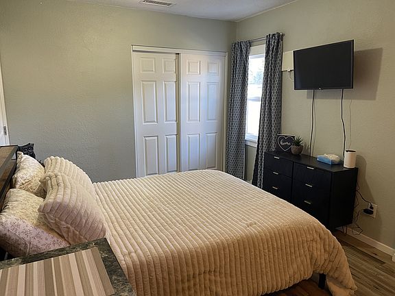 Queen-size bed with mounted flat-screen TV and ample closet storage in this fully furnished studio.