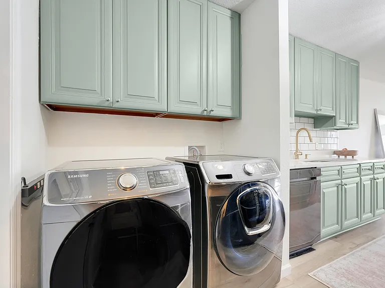 In-unit laundry with washer and dryer included, complemented by overhead cabinetry for added storage.