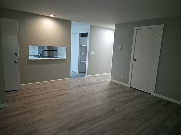 Living room showing kitchen entry and hallway and guest closet with all new vinyl flooring and paint.