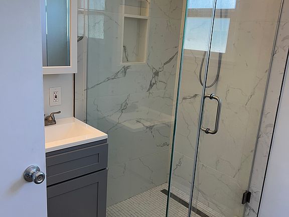 Newly remodeled bathroom with step-in shower with glass barn door type entrance.