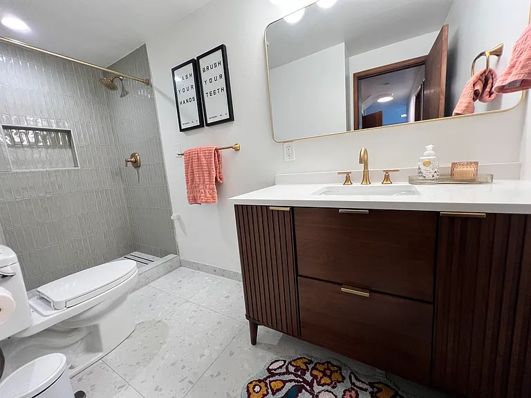 Lower-level bathroom was recently remodeled and features a wood vanity with stone counter, tiled floor and shower, Kohler fixtures, and Toto toilet.
