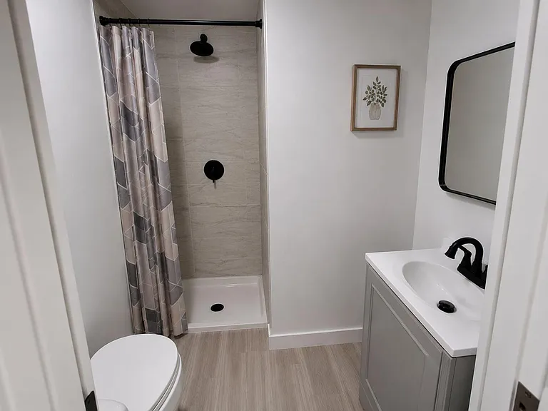 Updated bathroom with a walk-in shower, tile surround, and a modern vanity with ample counter space and mirror.