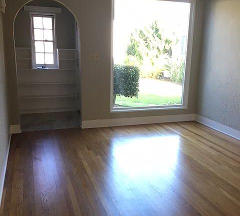 Entryway with built in book shelves. Large window in the living room, overlooking the grassy courtyard.