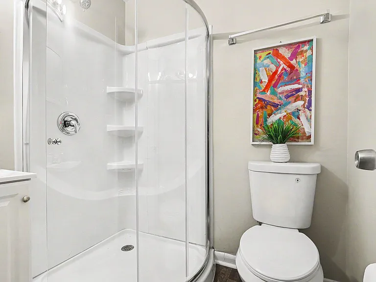 Bathroom with a corner shower enclosure, built-in shelving, and vanity storage for everyday essentials.