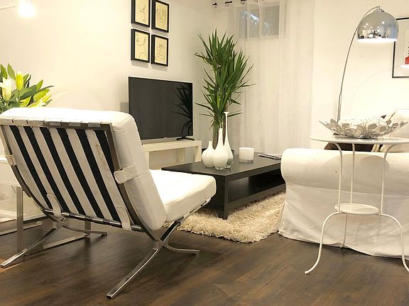 White modern Barcelona chair is designer piece but super comfy for reading too.