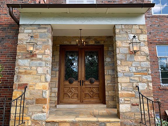 Stone portico with custom doors, wrought iron accents