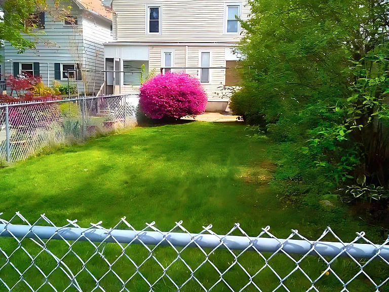 Fully-fenced, large grass rear yard. The concrete patio and fully-enclosed rear porch are in the background. Your car's reserved spot in the paved parking lot is the position this photo was taken from, right at the end of the yard!