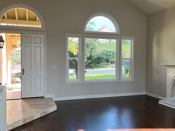 Front entrance into step-down formal living room with cathedral ceilings, lots of windows for natural light, fireplace