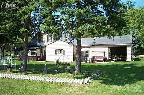 Rear view of the dwelling depicting the drive through garage door and flower garden and enclosed porch.