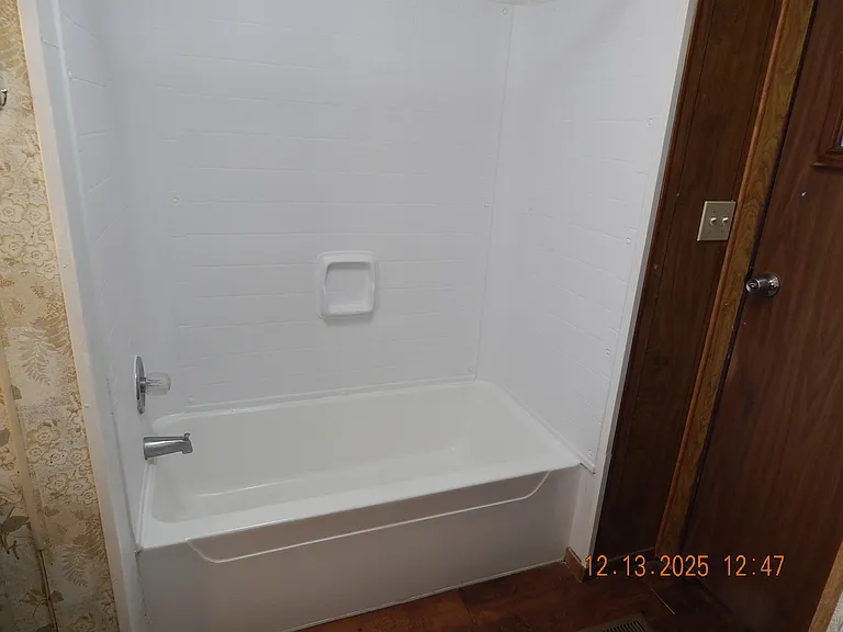 Bathtub with surround (shower curtain removed for this photo).