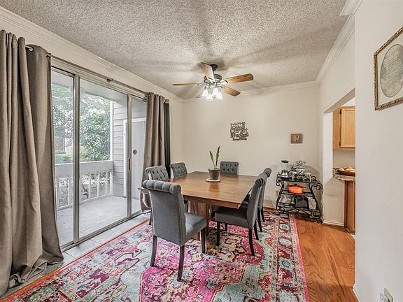 Dining space with ceiling fan, crown molding, light hardwood / wood-style flooring, and a textured ceiling. View of patio and gorgeous courtyard.