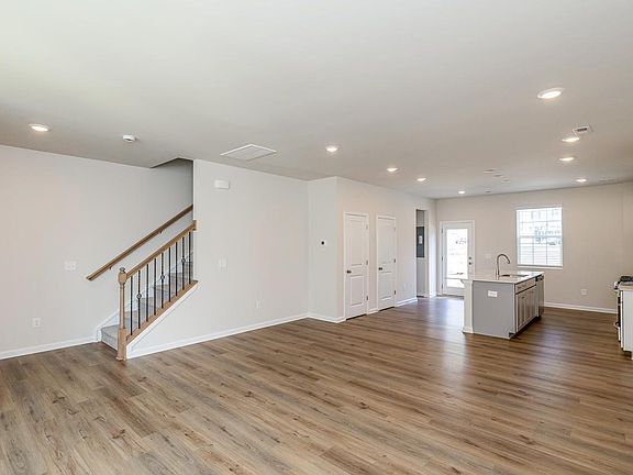 View from the living room into dining area, kitchen and back door leading to parking area. Steps on left lead to bedrooms and laundry area. The two doors on the left contain a coat closet and large pantry. The hot water heater is also located in the pantr