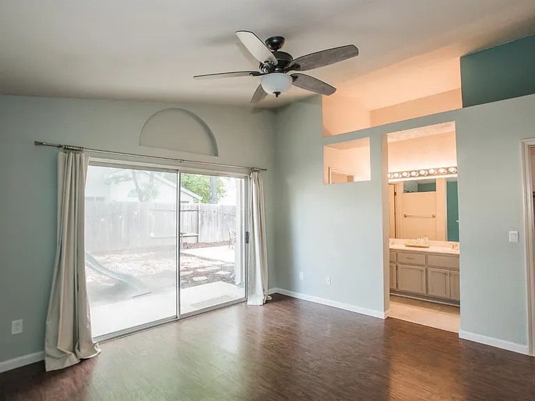 Master bedroom with ceiling fan & lights and sliding door to backyard
