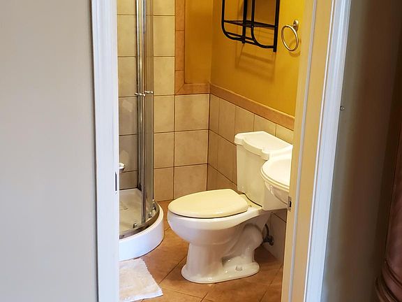 Bathroom with corner shower, pedestal sink can not be seen, large mirror with private storage behind it also not shown.
