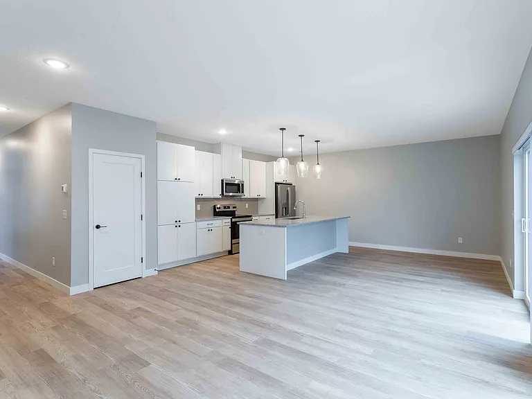 Modern open-concept kitchen with sleek cabinetry, stainless steel appliances, and elegant pendant lighting over a spacious island, perfect for entertaining.