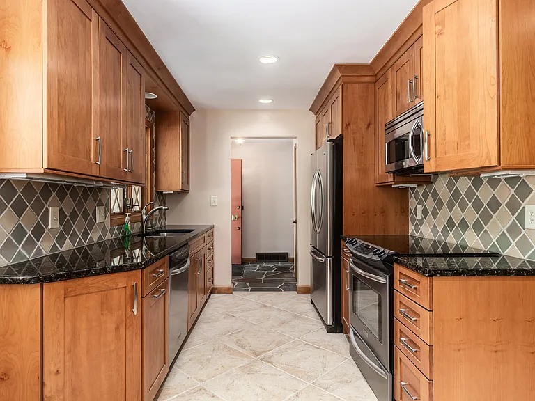 Fully equipped kitchen with stainless steel appliances, granite countertops, soft close natural wood customized cabinets with crown molding.