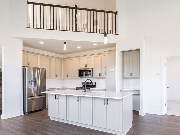 Island kitchen with light colored cabinets and wood floors at a DRB Homes Longstreet II plan at the