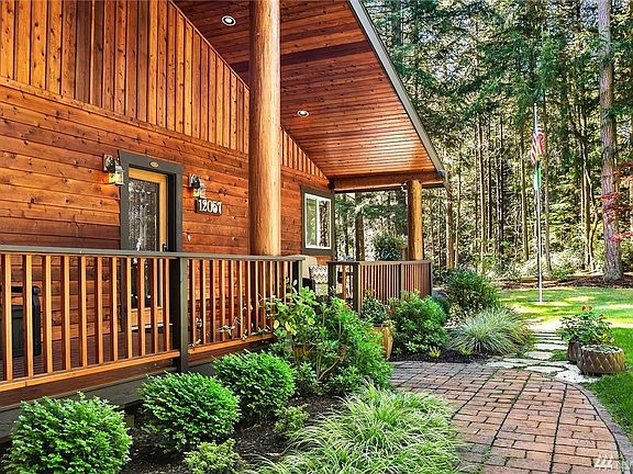 Brick entry path lined with inviting plants. View is from east to west. Entry door on left, up the steps.