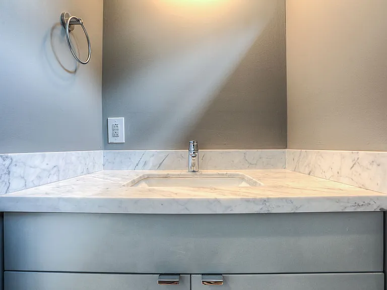 Powder room detail _ single-handle faucet on a Carrara marble vanity, gray cabinetry, and brushed-nickel towel ring
