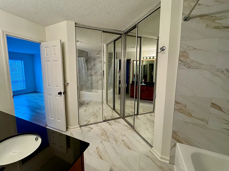 view of walk-in closet with mirrored doors, with bedroom seen at left