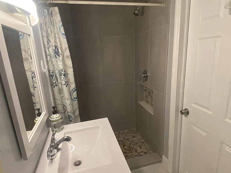 Bathroom with a tiled walk-in shower, niche shelving, and a single-sink vanity with mirror and overhead lighting.
