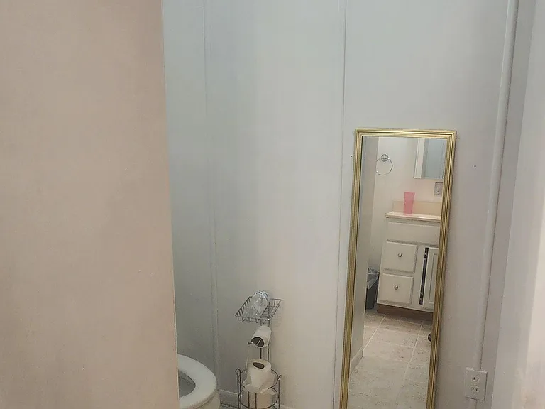 Compact bathroom with tile flooring and a vanity area visible in the mirror, offering practical everyday functionality.
