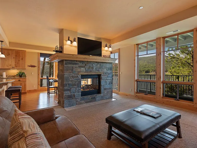 Open floor plan with living room, dining room, kitchen, and warming dual-sided fireplace, southern exposure.