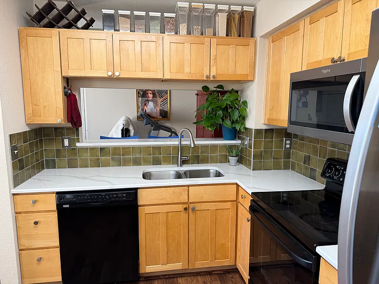 Kitchen with new quartz countertops, tile backsplash, sink, faucet and microwave. Large stainless steel fridge. Technically is the size of an "eat-in" kitchen.