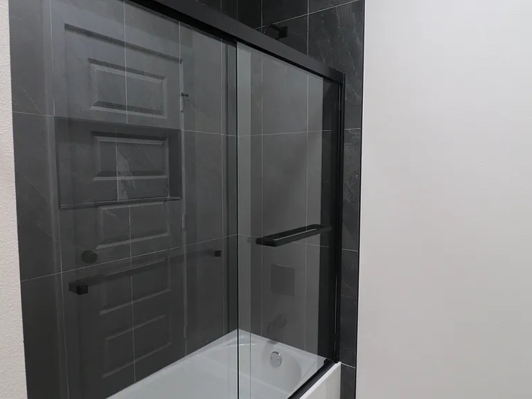 Beautiful tub and shower combination with floor-to-ceiling tile and a sleek glass enclosure.