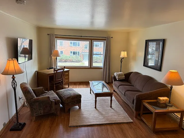 Living Room. Furnished with TV, desk, couch, chair, lamps, etc.