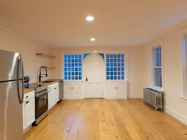 The kitchen is set up with beautiful appliances, a butcher block counter, new cabinets, and plenty of space for a dining area with lots of natural light.