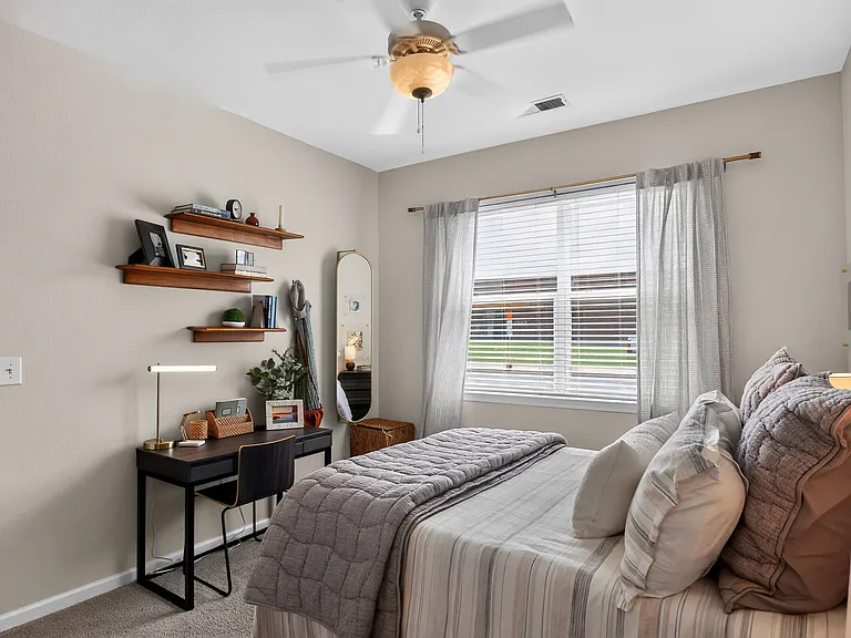 A cozy bedroom at Ralston Apartments in Downtown Indianapolis, featuring soft decor, plush bedding, and an ensuite bathroom with modern finishes.