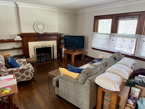 Living room with natural fireplace & built in shelving. Also features crown molding and hardwood floors