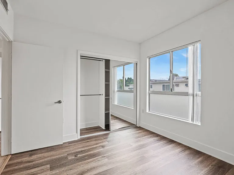 Bedroom with Mirrored Closet with Shelving, Vinyl Flooring, and Windows