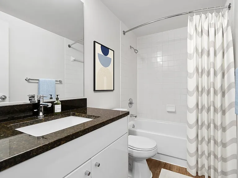 Renovated Package I bath with white cabinetry, black granite countertops, and hard surface flooring