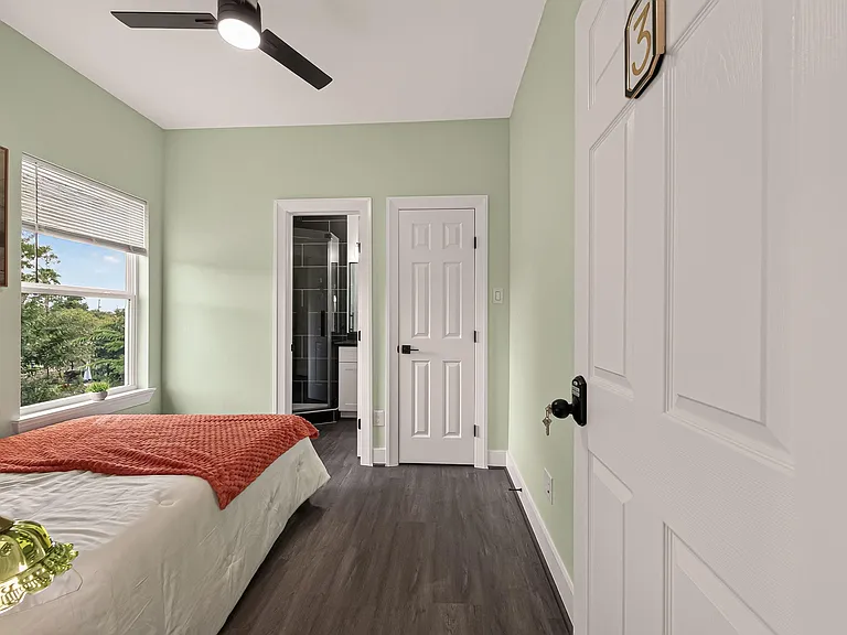 Private bedroom with a large window, ceiling fan, and easy access to an en-suite bath plus nearby closet storage.
