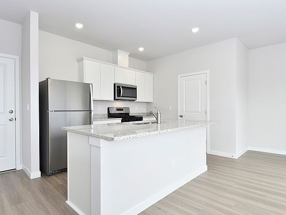 The kitchen has stainless steel appliances and plank flooring.