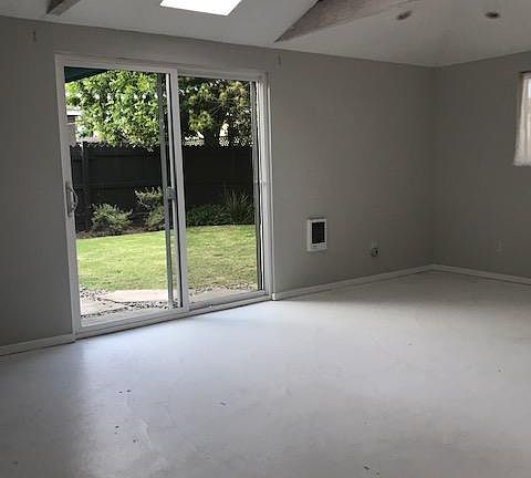 Bedroom w/ high vaulted ceiling, skylight & door to backyard