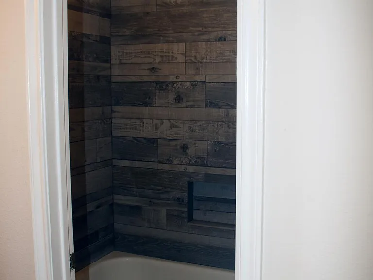 Fully remodeled master bathroom tub and shower with wall-to-wall imported tile with insert, and bronze fixtures.