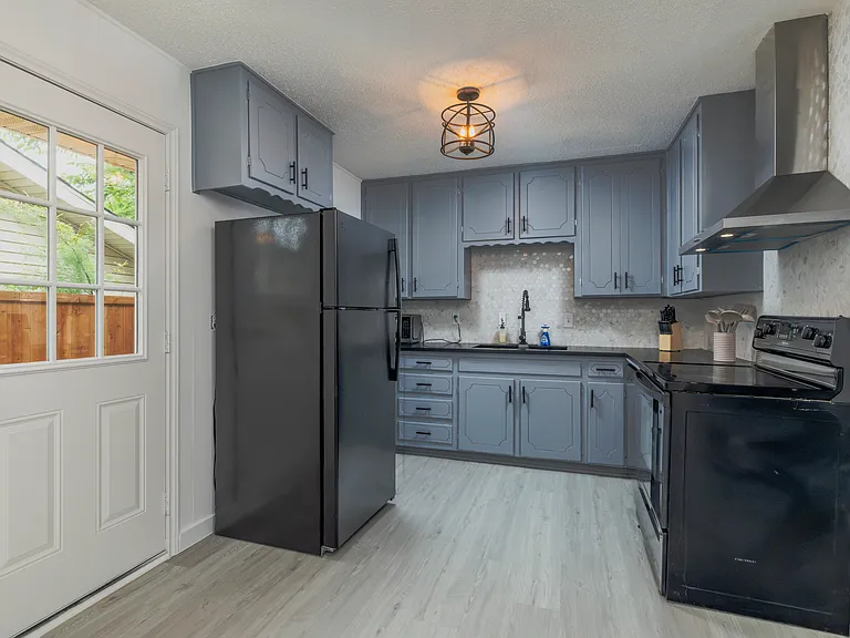 Fully stocked kitchen with a stainless steel range hood and cooking essentials