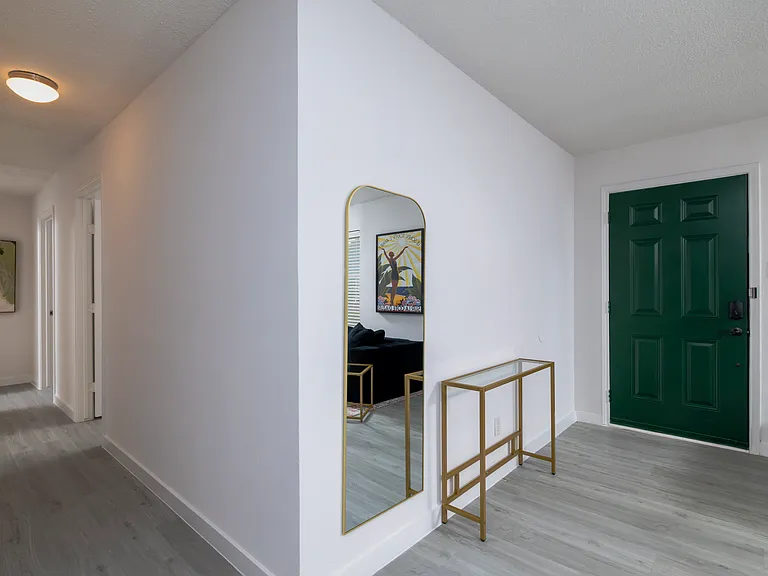 Private front entrance with a full length mirror and glass table.