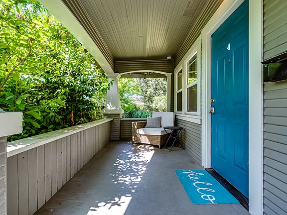 Front porch tucked behind lush green hedges offers privacy from the street view.