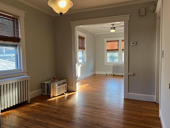 Open Dining/LIving with gleaming antique hardwood floors and original trim. Wood blinds, AC unit included.