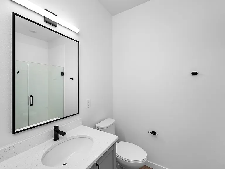 Modern bathroom with a sleek design, featuring a large mirror, elegant black fixtures, and a pristine glass-enclosed shower. Modern bathroom with a sleek design, featuring a large mirror, elegant black fixtures, and a pristine glass-enclosed shower.