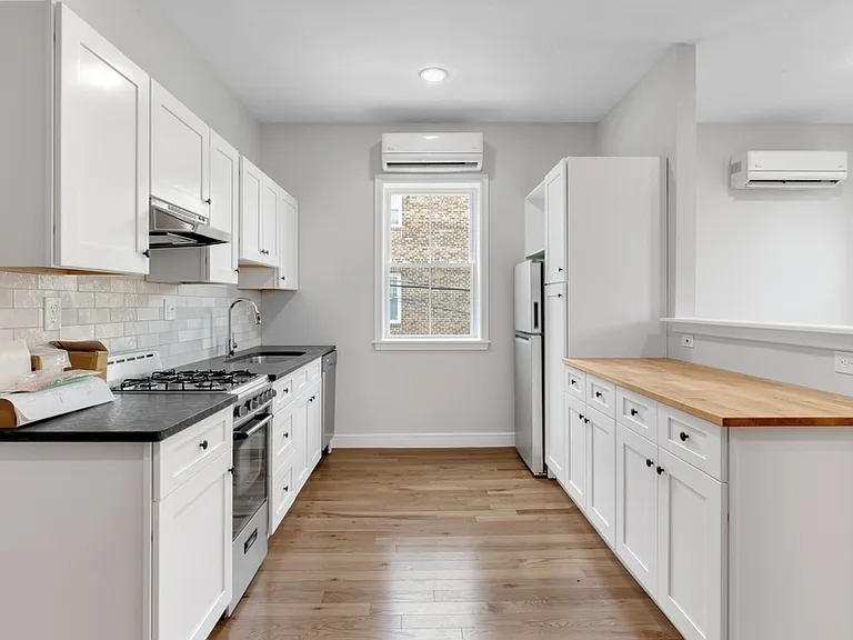 Modern kitchen has tile backsplash, stainless steel appliances, and shaker cabinets.